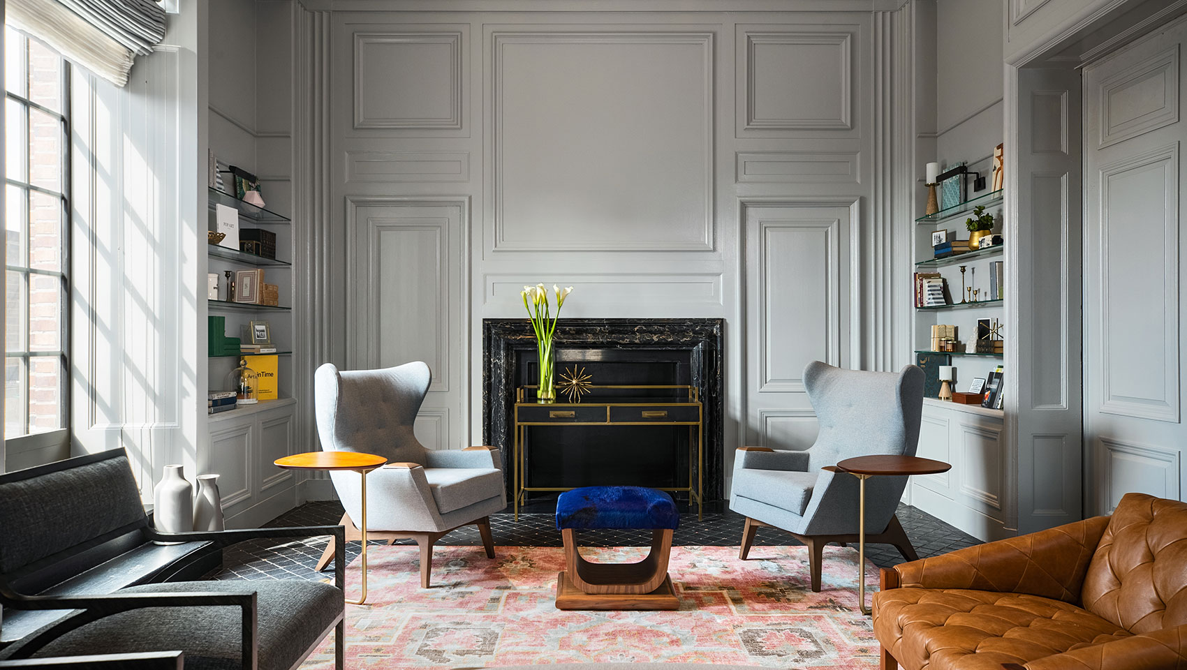 Kimpton Hotel Palomar Philadelphia AIA Library showing accent chairs surrounding a fireplace with bookshelves on the left and right wall