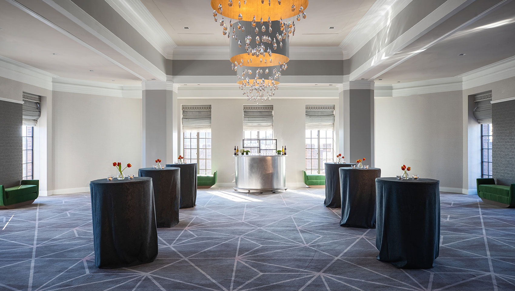 Ballroom social reception set up at Kimpton Hotel Palomar Philadelphia with cocktail tables throughout open area underneath circular chandeliers in the center of the room 