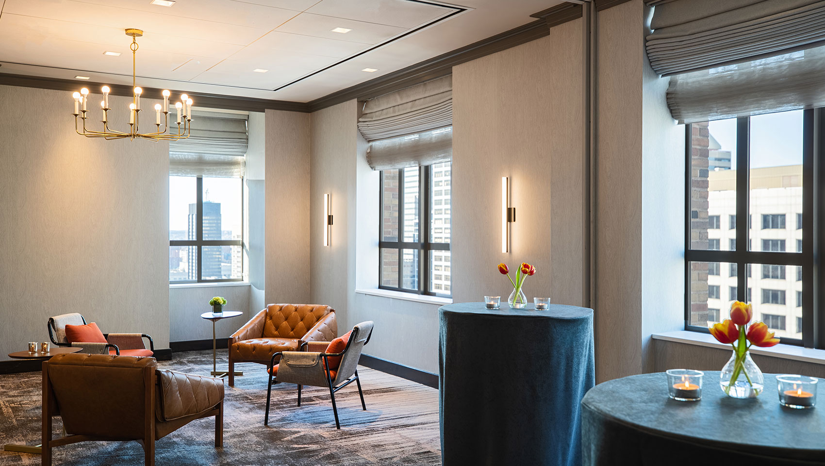 Social cocktail reception set up at Kimpton Hotel Palomar Philadelphia’s Wright room with two high tables with candles and floral arrangements next to lounge seating