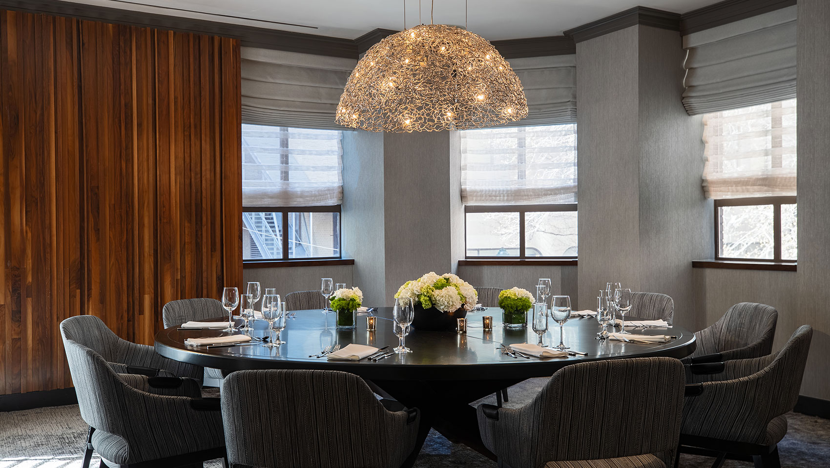 Pei Private Dining Setup in an intimate room with round table that has a floral centerpiece and multiple place settings with glassware and utensils 