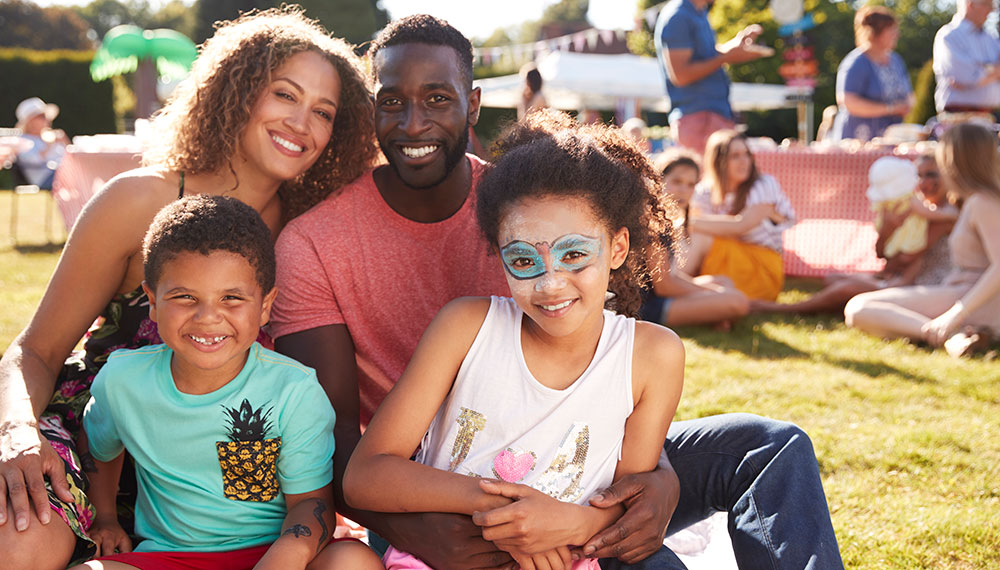 Family of Four sitting on the grass at a celebration