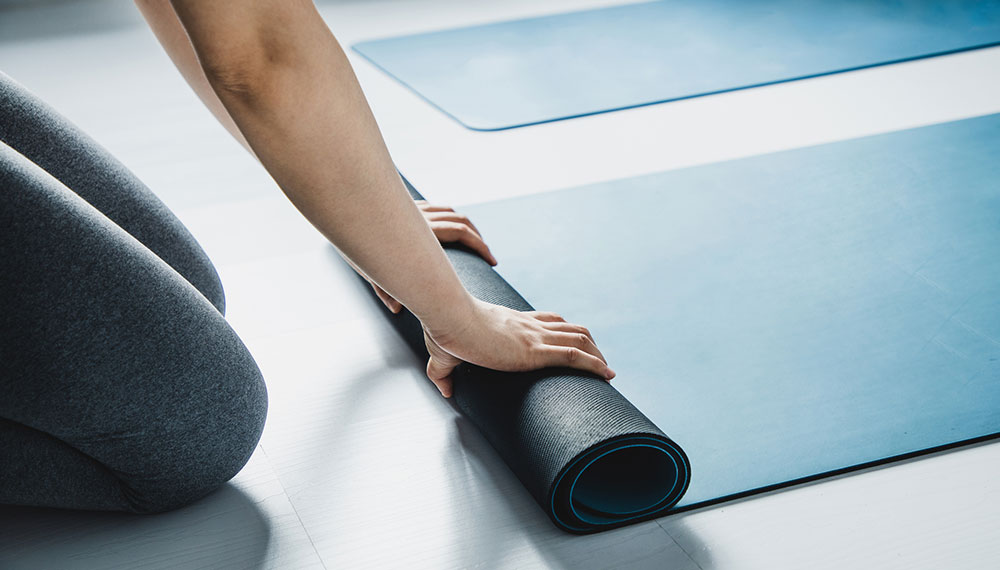 Woman rolling up yoga mat