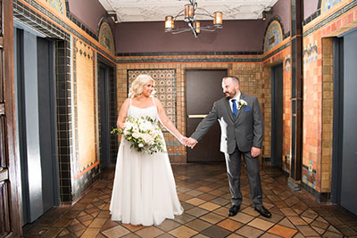 bride and groom in front of a mosaic wall