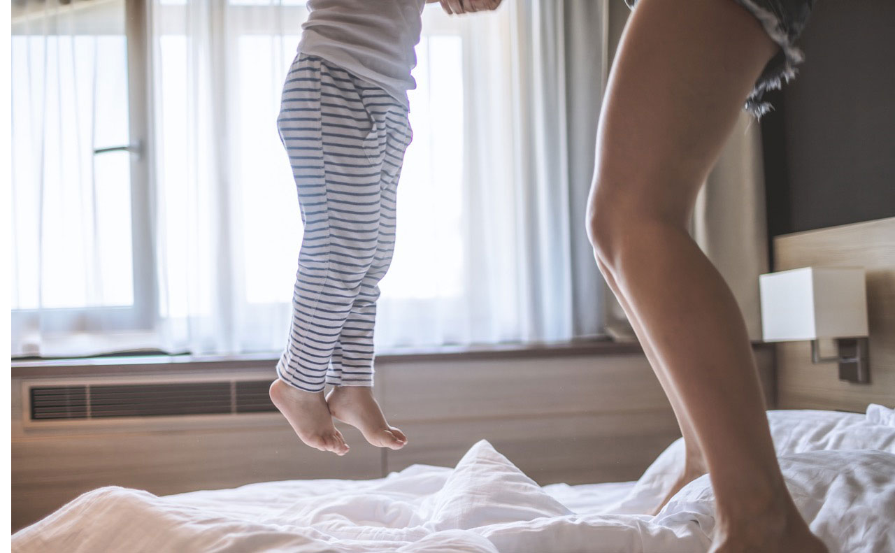 mom and kid jumping on hotel bed