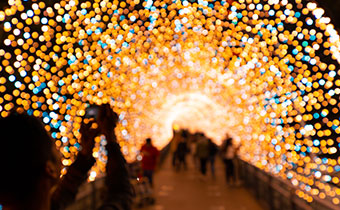 people walking through tunnel of twinkling lights